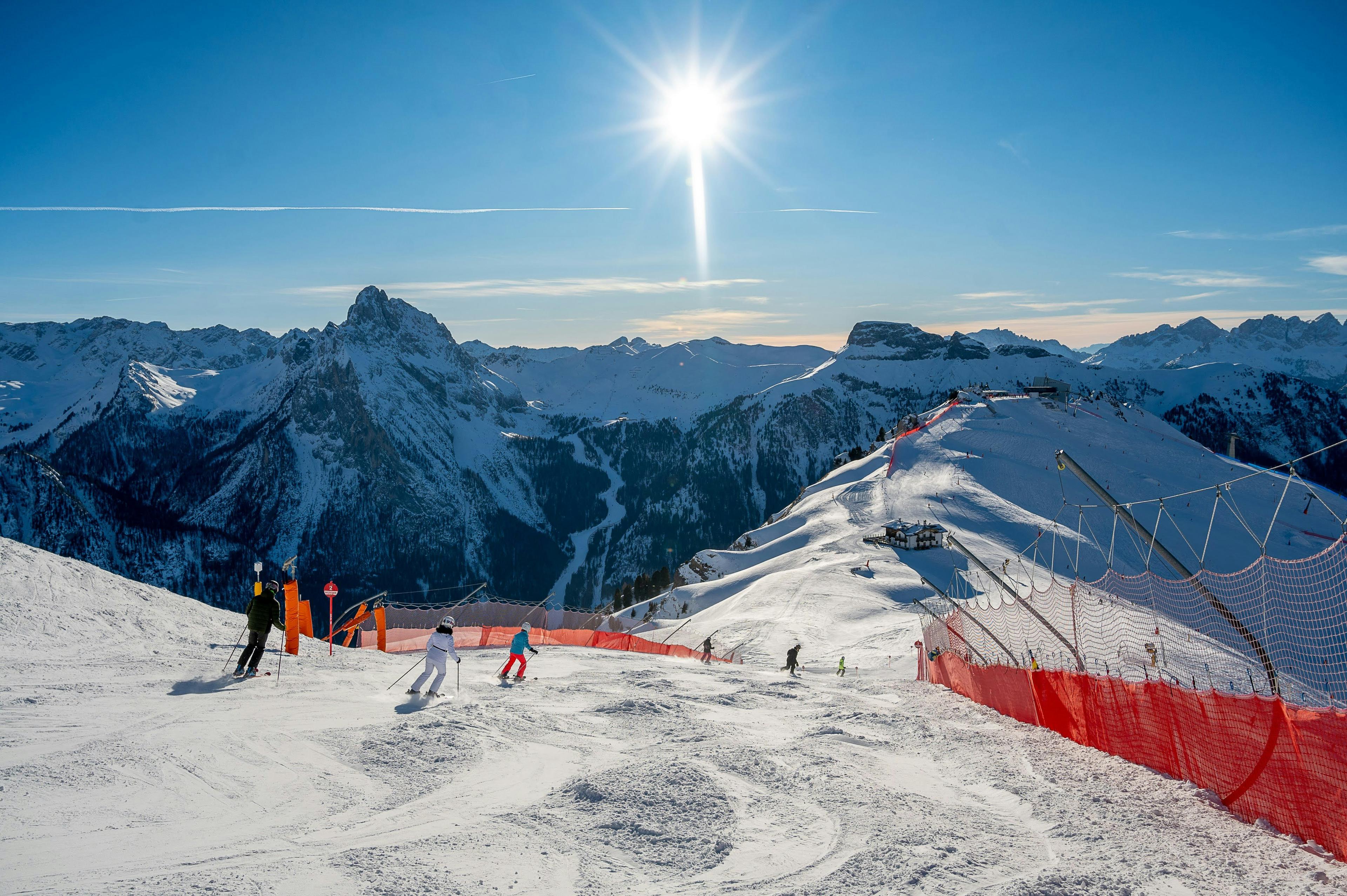 Uitzicht over de bergen met enkele skiers op de piste in de zon
