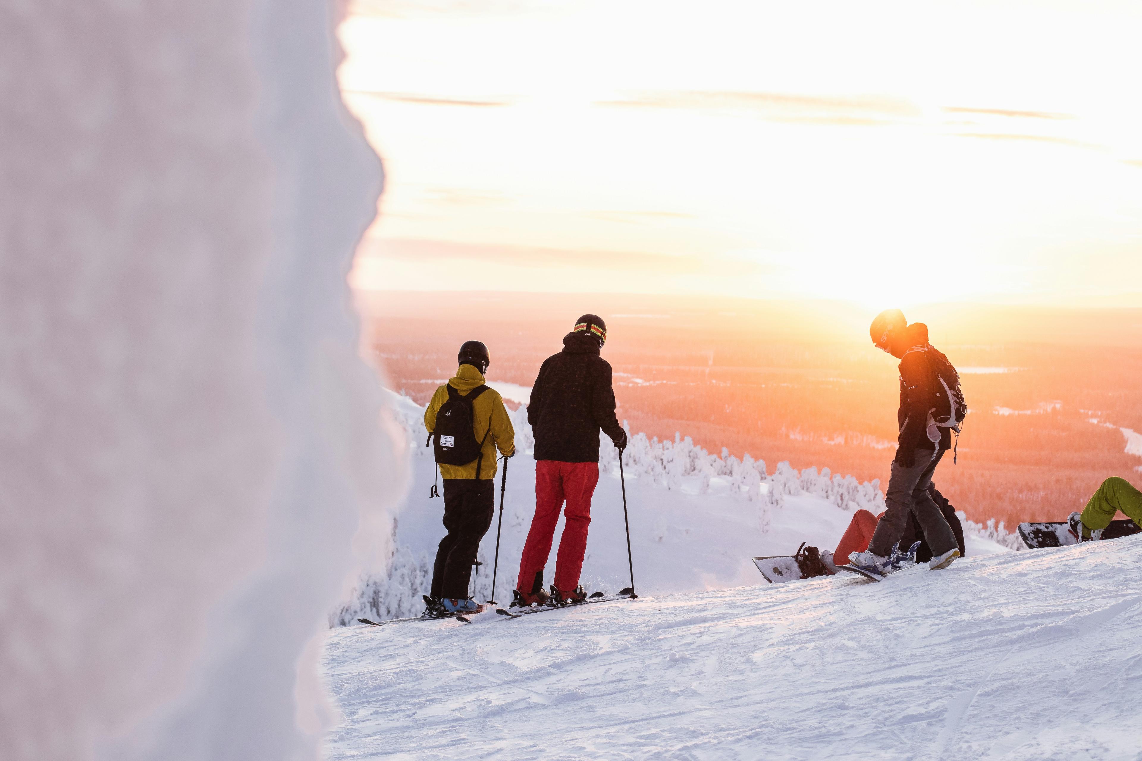 Drie skiers kijken prachtige vallei in met opkomende zon