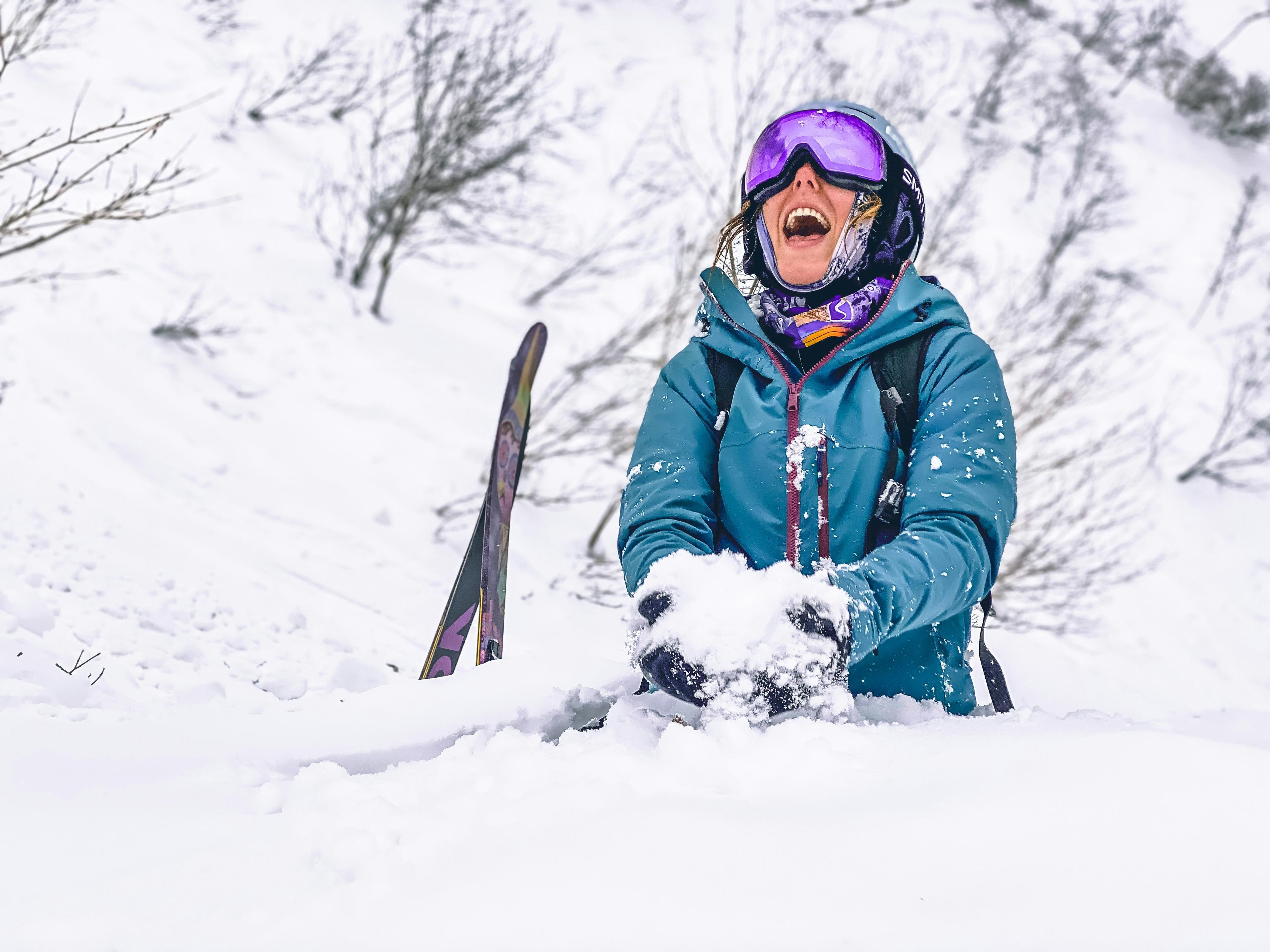 Persoon lachend en spelend in de diepe poeder sneeuw