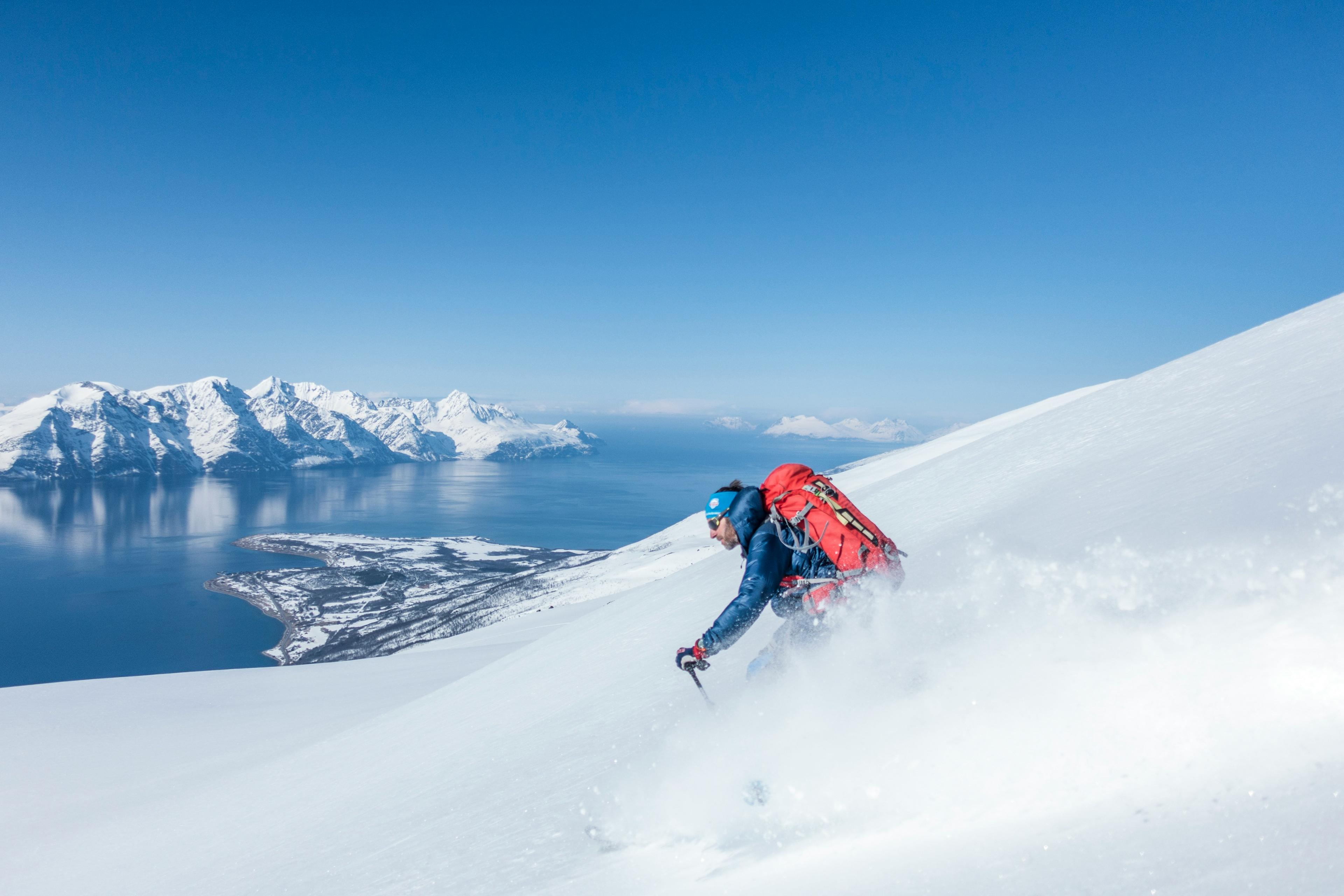 Skier in noorwegen in poedersneeuw met fjord op de achtergrond